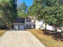 Two-story home features a two-car garage, complemented by a well-kept lawn and trees at 2015 Aldbury Ln, Woodstock, GA 30189