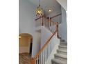 Staircase with wooden handrail, white banisters, modern lighting fixture, and neutral wall color at 2015 Aldbury Ln, Woodstock, GA 30189