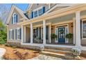 Inviting covered front porch with rocking chairs, columns, and a blue front door at 7270 Sheffield Pl, Cumming, GA 30040