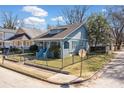 View of a blue bungalow home, highlighting its cozy front porch and black fenced yard on a sunny day at 1000 Beckwith Sw St, Atlanta, GA 30314