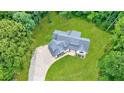 An aerial view of the beautiful home showing the roof, landscaping, driveway, and surrounding lush greenery at 836 Bailey Woods Rd, Dacula, GA 30019