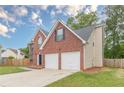 Side view of brick home featuring a two-car garage, a combination brick and vinyl exterior and fenced yard at 105 Kentwood Springs Dr, Hampton, GA 30228