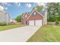 Well-maintained brick home showcasing a long driveway leading to a two-car garage and mature trees at 105 Kentwood Springs Dr, Hampton, GA 30228