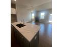 Kitchen island with marble countertop, dark cabinets, a sink, and a view of the living area fireplace at 270 Lakeside Pl, Canton, GA 30114