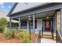 Inviting front porch with gray columns and stone accents, leading to a red front door and landscaped surroundings at 830 Village Manor Pl, Suwanee, GA 30024