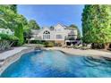 Luxury backyard oasis featuring a stunning pool, stone waterfall, and comfortable patio seating at 973 Meadow Club Ct, Suwanee, GA 30024