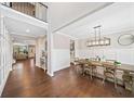Open-concept dining room features hardwood floors, wainscoting, a modern light fixture, and a view of the living area at 1599 Benham Dr, Snellville, GA 30078