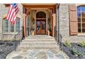 Stone steps lead to a front porch featuring double doors, sconces, and a wrought iron railing at 3820 N Berkeley Lake Nw Rd, Berkeley Lake, GA 30096