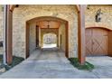 Covered driveway featuring brick and stone and leading to a wooden garage door at 3820 N Berkeley Lake Nw Rd, Berkeley Lake, GA 30096