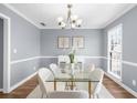 Elegant dining room with modern glass table, white chairs, and soft, neutral decor at 310 Mulberry Manor Ct, Johns Creek, GA 30005
