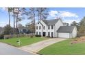 Traditional two-story white home with an attached garage, situated on a well-kept lawn at 310 Mulberry Manor Ct, Johns Creek, GA 30005