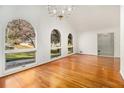 Bright living room featuring hardwood floors, elegant chandelier, and large arched windows offering ample natural light at 4551 Cherie Glen Trl, Stone Mountain, GA 30083