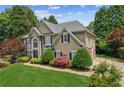 Charming two-story home with a lush lawn, mature trees, and an American flag at 2115 Brook Pond Ct, Alpharetta, GA 30005