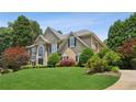 Charming two-story home with a lush lawn, mature trees, and an American flag at 2115 Brook Pond Ct, Alpharetta, GA 30005