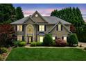 Charming two-story home featuring manicured landscaping, lush lawn and mature trees at dusk at 2115 Brook Pond Ct, Alpharetta, GA 30005