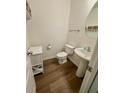Well-lit powder room featuring a pedestal sink and wood-look floors at 3032 Cedar Glade Ln, Buford, GA 30519