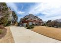 Brick home featuring an expansive driveway, lush lawn, and manicured landscaping at 720 First Cotton Dr, Powder Springs, GA 30127