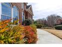 Close-up on the side of a brick house with colorful shrubs and a concrete walkway at 720 First Cotton Dr, Powder Springs, GA 30127