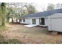 A simple backyard with a white slab patio, shed, and the home's exterior, enclosed by trees at 5928 Seam St, Lithonia, GA 30058