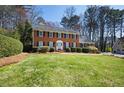 Traditional two-story brick home featuring a lush front lawn and manicured landscaping with a white front door at 1121 Valley Ridge Se Ct, Marietta, GA 30067