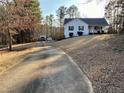 View of a one-story home with long concrete driveway, mature trees, and nice landscaping at 140 Thrasher Rd, Covington, GA 30016