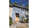 Two-story townhome with light blue siding and white trim with overgrown front yard and boarded front door at 524 Northridge Crossing Dr, Atlanta, GA 30350