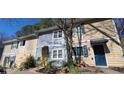 Two-story townhomes with siding of light blue and tan, and overgrown landscaping at 524 Northridge Crossing Dr, Atlanta, GA 30350