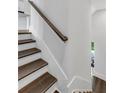 Staircase with dark wood treads, white walls and a simple wood handrail at 587 Red Clay Farm Ln, Suwanee, GA 30024