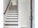 Inviting stairway featuring wood handrail and white risers leading to upper levels of the home at 557 Red Clay Farm Ln, Suwanee, GA 30024