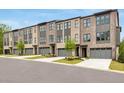 A row of brick townhomes with garages, landscaping, concrete driveways, and windows with dark trim at 577 Red Clay Farm Ln, Suwanee, GA 30024