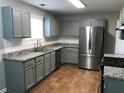 Well-lit kitchen boasting granite countertops, stainless steel refrigerator, gray cabinets and wood flooring at 2143 Gwinn Dr, Norcross, GA 30071