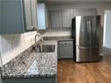 Close up of kitchen featuring stainless steel refrigerator, granite countertops, gray cabinets and wood flooring at 2143 Gwinn Dr, Norcross, GA 30071