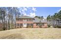 Traditional red brick house with black shutters on a sunny day highlighting the green lawn at 5020 Puritan Dr, Sugar Hill, GA 30518