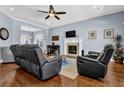 Comfortable living room featuring a fireplace, ceiling fan, and leather furniture with hardwood flooring at 9204 Malcolm Dr, Covington, GA 30014