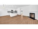 Open living space featuring a fireplace, wood floors, and a modern kitchen with stainless appliances at 11961 Lovejoy Crossing Way, Hampton, GA 30228