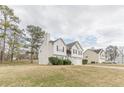 Angle view of a charming two-story home with white siding, a brick entryway, attached two-car garage, and landscaped front yard at 71 Farm St, Hiram, GA 30141