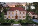 Elegant stone home featuring a formal garden with fountain, arched entryway, and picturesque surroundings at dusk at 4975 Rebel Trl, Atlanta, GA 30327