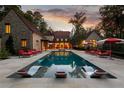 Luxurious outdoor swimming pool with lounge chairs and sun umbrellas at dusk at 4975 Rebel Trl, Atlanta, GA 30327