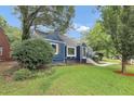 Side view of a blue bungalow with manicured lawn and mature trees at 3423 Rugby Cir, Atlanta, GA 30337