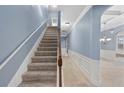Carpeted staircase with wooden handrail, complemented by decorative wall trim and soft blue paint at 825 Bufflehead Ct, Stockbridge, GA 30281