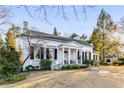 Elegant white home with black shutters, a columned porch, and mature trees in a lush yard at 2 W Muscogee Nw Ave, Atlanta, GA 30305