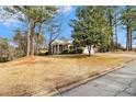 Brick house with a columned front porch on a tree-lined lot, showcasing its serene setting at 405 Putting Green Ln, Roswell, GA 30076