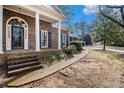 Inviting front porch featuring brick steps, a classic door, and black shuttered windows at 405 Putting Green Ln, Roswell, GA 30076
