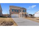 Two-story brick home with two-car garage, covered front porch and a long concrete driveway with a lawn at 237 Chiswick Loop, Stockbridge, GA 30281