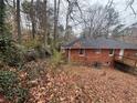 Back of a brick home with a wooden deck, a few windows, and a wooded lot surrounded by trees and foliage at 1900 Calloway Nw Dr, Atlanta, GA 30314