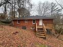 Rear exterior view of a brick home with a wooden deck, backyard stairs and a wooded lot at 1900 Calloway Nw Dr, Atlanta, GA 30314