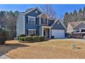 Inviting two-story home showcasing blue siding, stone detail, manicured bushes, and an attached two-car garage at 537 Quinn Dr, Woodstock, GA 30188