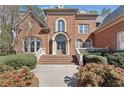 Elegant brick home entrance with stately columns, arched windows, and manicured landscaping at 2821 Grey Moss Pass, Duluth, GA 30097