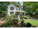 Two-story home with a covered front porch, surrounded by lush greenery and mature trees at 3003 Maple Ln, Alpharetta, GA 30009