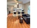 Open concept kitchen with white cabinetry, island seating, stainless appliances and wood floors at 3868 Demooney Rd, Atlanta, GA 30349